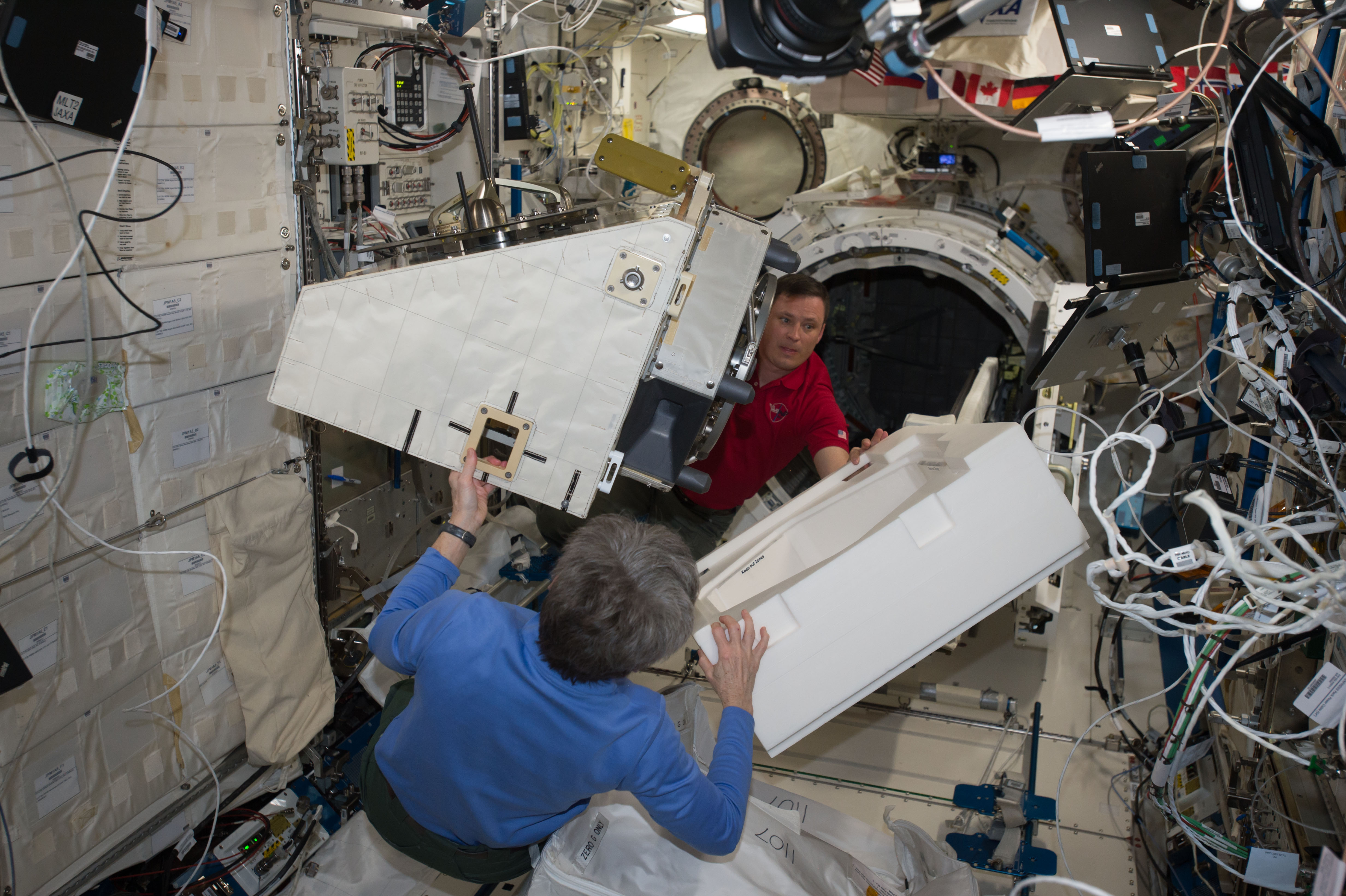 iss051e028168 - (4/25/2017) --- NASA astronauts Peggy Wilson, in blue, Jack Fischer move a new payload on to the NanoRacks External Platform to prepare for deployment via an airlock in the Japanese Experiment Module on the International Space Station. Credits: NASA