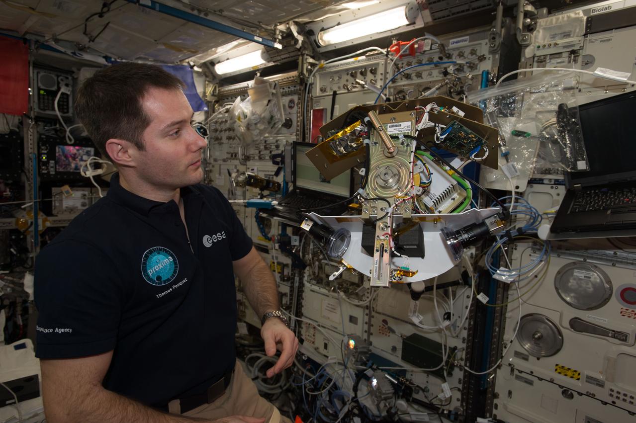 iss051e033986 (5/2/2016) --- European Space Agency (ESA) astronaut Thomas Pesquet is photographed with the assembled Science Arm and Motor for the Fluid Dynamics in Space (FLUIDICS) experiment. Image was taken in the Columbus European Laboratory during preparations for the first run of the experiment. The FLUIDICS investigation evaluates the Center of Mass (CoM) position regarding a temperature gradient on a representation of a fuel tank. The observation of capillary wave turbulence on the surface of a fluid layer in a low-gravity environment can provide insights into measuring the existing volume in a sphere.