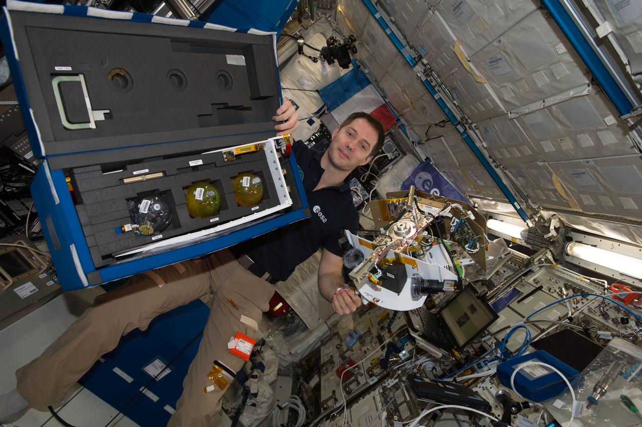 iss051e033988 (5/2/2017) --- European Space Agency (ESA) astronaut Thomas Pesquet is photographed with the Tanks Bag and Science Arm for the Fluid Dynamics in Space (FLUIDICS) experiment. Image was taken in the Columbus European Laboratory during preparations for the first run of the experiment. The FLUIDICS investigation evaluates the Center of Mass (CoM) position regarding a temperature gradient on a representation of a fuel tank. The observation of capillary wave turbulence on the surface of a fluid layer in a low-gravity environment can provide insights into measuring the existing volume in a sphere.