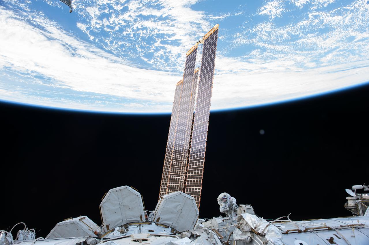 iss053e079613 (Oct. 5, 2017) --- NASA astronaut Randy Bresnik (bottom center) is dwarfed by a set of basketball court-sized solar arrays and the Earth in the background during a spacewalk on Oct. 5, 2017.