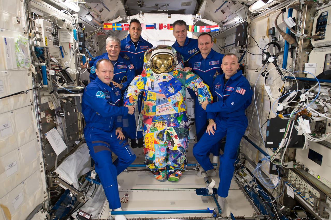 iss053e180226 (Nov. 12, 2017) --- The six-member Expedition 53 crew poses for a portrait inside the Japanese Kibo laboratory module with a spacesuit hand-painted by cancer patients from the M.D. Anderson Cancer Center in Houston. On the left (from top to bottom) are NASA astronauts Joe Acaba and Mark Vande Hei with cosmonaut Alexander Misurkin of Roscosmos. On the right (from top to bottom) are European Space Agency astronaut Paolo Nespoli, cosmonaut Sergey Ryazanskiy of Roscosmos and Expedition 53 Commander Randy Bresnik of NASA.