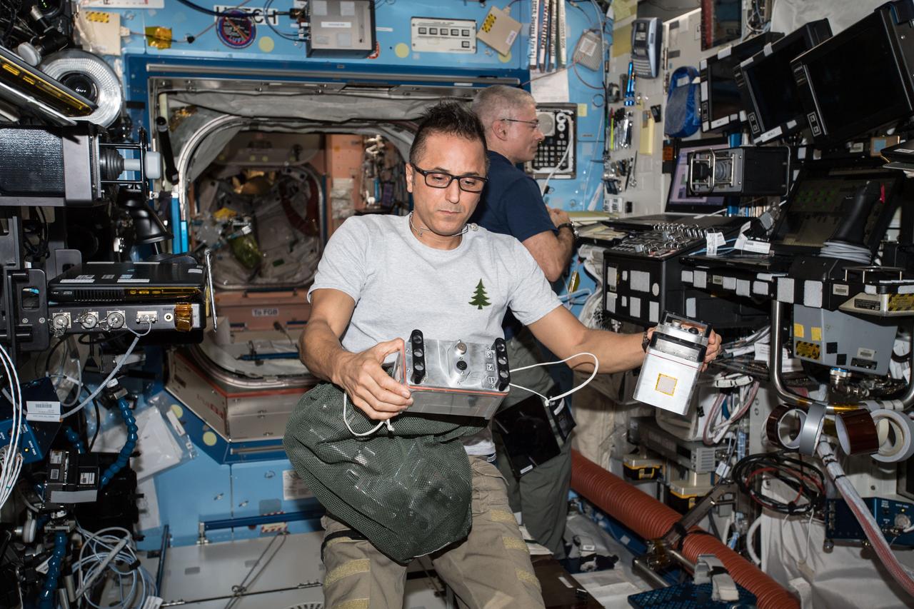 iss054e001472 (Dec. 19, 2017) --- NASA astronaut Joe Acaba with Biological Research in Canisters - Light Emitting Diode (BRIC-LED) canisters in the Destiny Laboratory prior to installation to provide capabilities for seedling, microbial, or fungal growth investigations. NASA astronaut Mark Vande Hei is visible in the background.