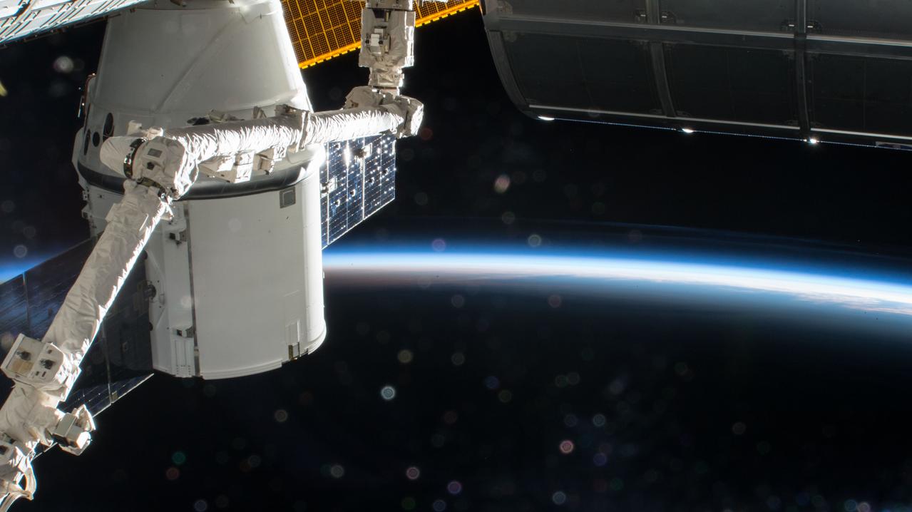 iss054e002538 (Dec. 24, 2017) --- The SpaceX Dragon is pictured with the Canadarm2 robotic arm in the foreground and the Earth's limb in the background as the International Space Station soars into an orbital sunrise during Expedition 54.