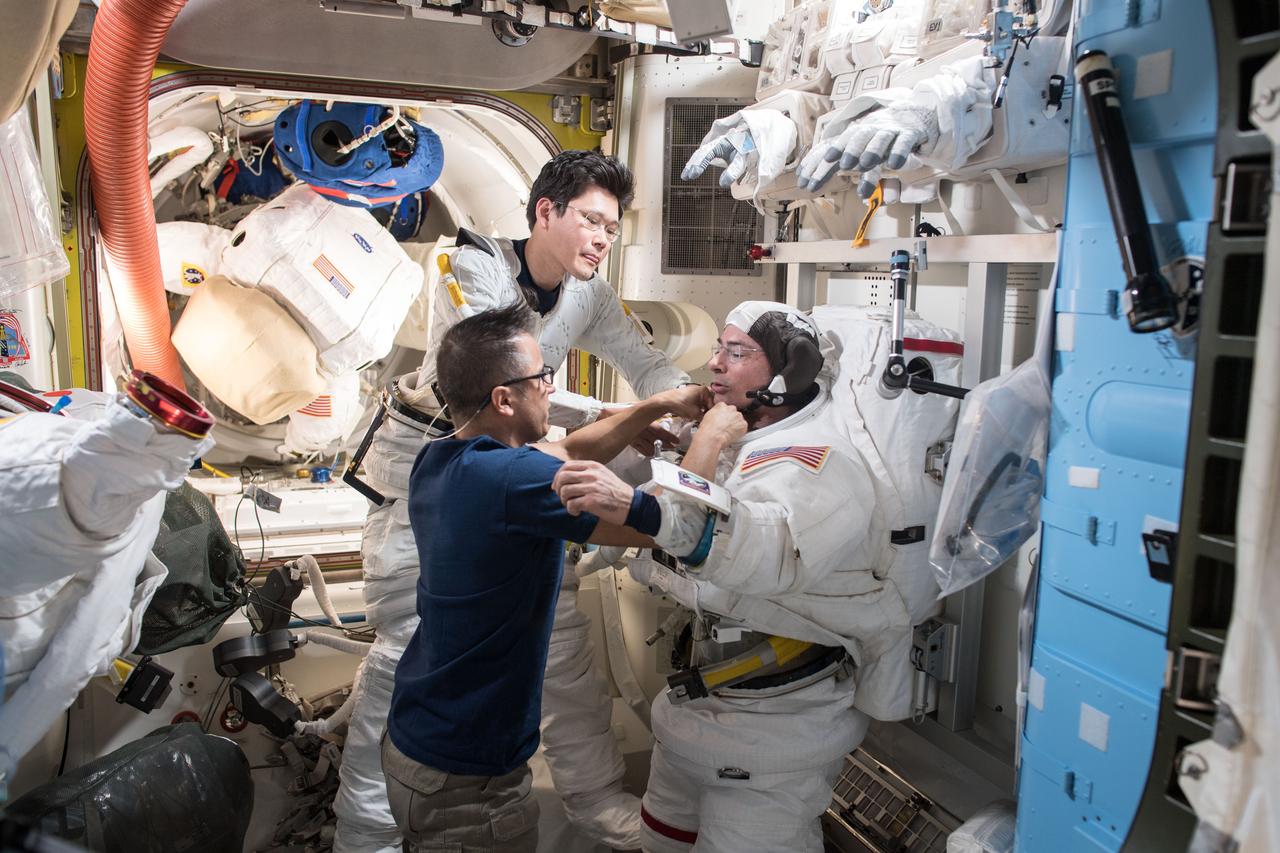 iss054e022293 (Jan. 18, 2018) --- Astronaut Joe Acaba (clockwise from bottom) assists spacewalkers Norishige Kanai, from the Japan Aerospace Exploration, and Mark Vande Hei, from NASA, during a fit check of their U.S. spacesuits. Kanai and Vande Hei will conduct a spacewalk Jan. 29 wrapping up work on a Latching End Effector from the Canadarm2.