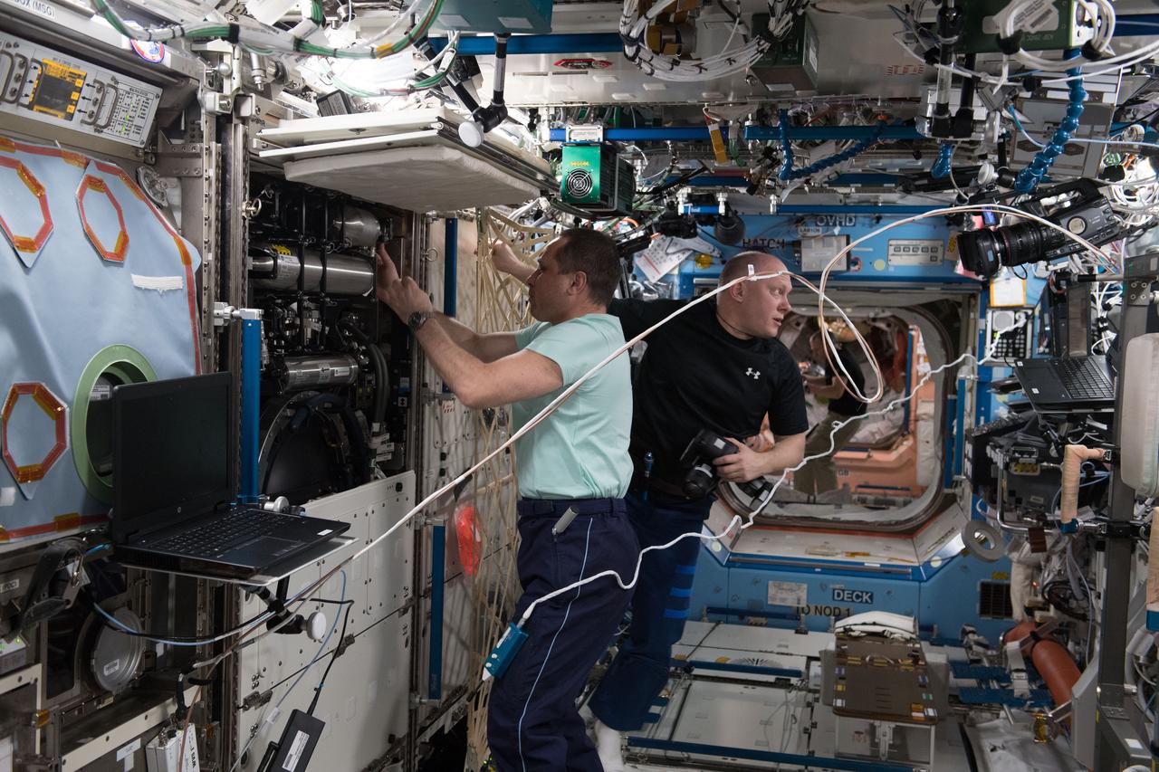 iss055e005587 (March 26, 2018) --- Expedition 55 Commander Anton Shkaplerov (foreground) and Flight Engineer Oleg Artemyev, both cosmonauts representing Roscosmos, replace manifold bottles inside the the Destiny lab module's Combustion Integrated Rack.