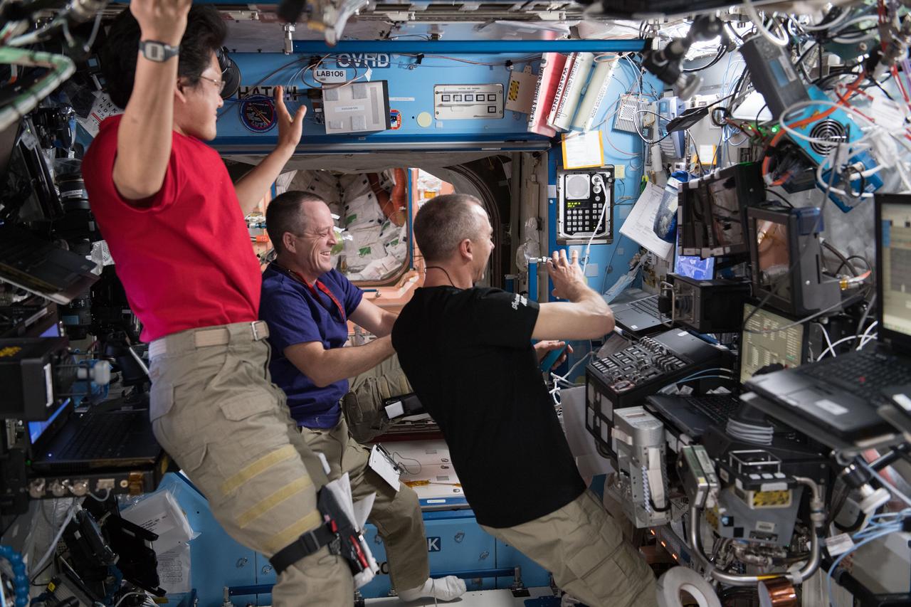 iss055e005656 (March 26, 2018) --- Expedition 55 Flight Engineers (from left) Norishige Kanai, Ricky Arnold and Drew Feustel gather inside the Unity module and take part in a spacewalk procedure conference with specialists on the ground at the Mission Control Center in Houston, Texas.