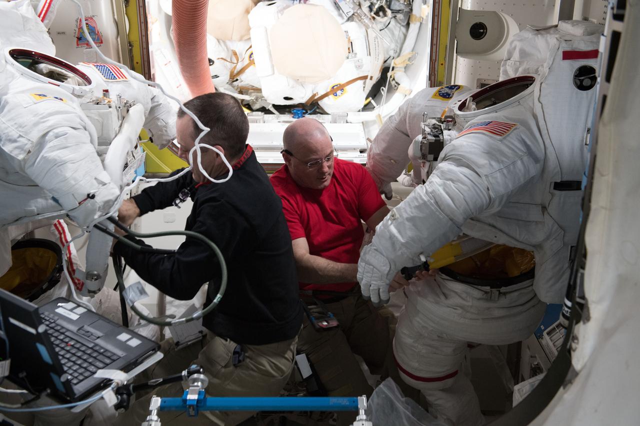 iss055e008292 (April 2, 2018) --- Astronauts Ricky Arnold and Scott Tingle scrub water cooling loops inside a pair of U.S. spacesuits after the completion of spacewalk on March 29, 2018.