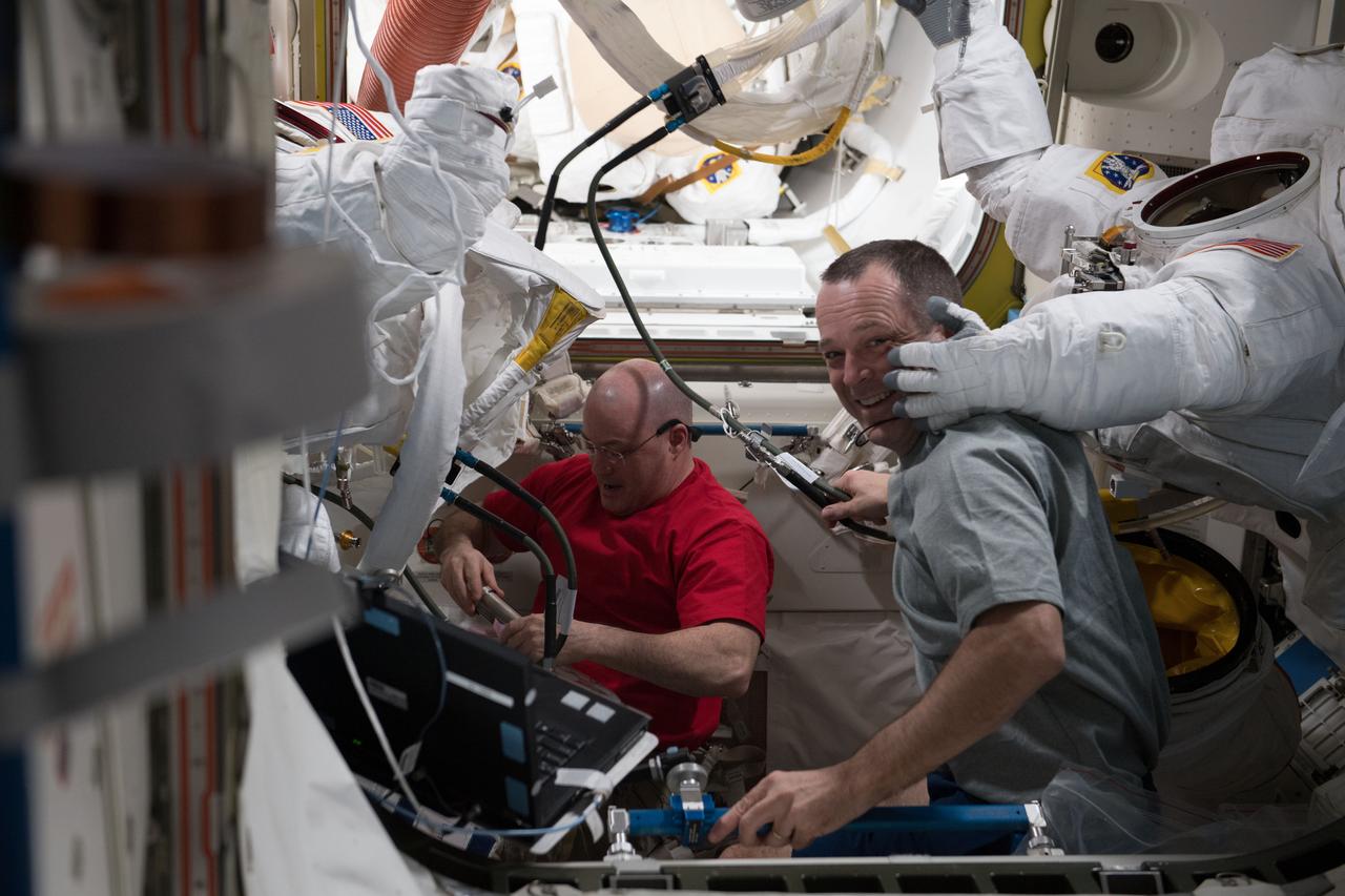iss055e008298 (April 2, 2018) --- Astronauts Scott Tingle (left) and Ricky Arnold wrap up spacesuit work following a successful spacewalk on March 29, 2018. The duo scrubbed cooling loops, performed the iodination of ion filters and tested the water conductivity inside a pair of U.S. spacesuits.