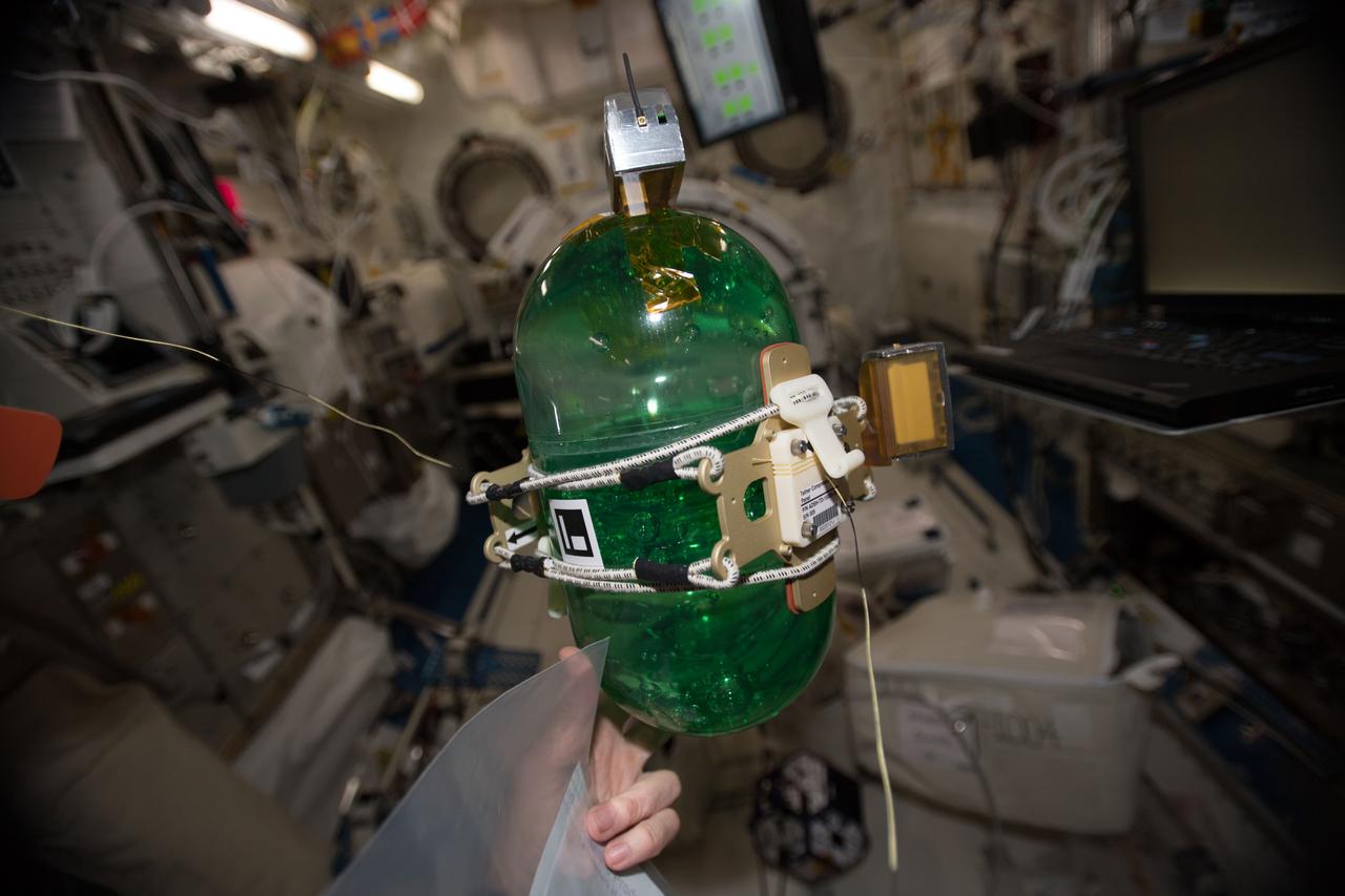 iss055e010694 (4/4/2018) --- A view taken aboard the International Space Station (ISS) during the set up of the SPHERES Tether Slosh experiment hardware. The image is of the green SPHERES robots tethered to a fluid-filled container covered in sensors to test strategies for safely steering spacecraft such as dead satellites that might still have fuel in the tank. SPHERES Tether Slosh combines fluid dynamics equipment with robotic capabilities aboard the International Space Station to investigate automated strategies for steering passive cargo that contain fluids.