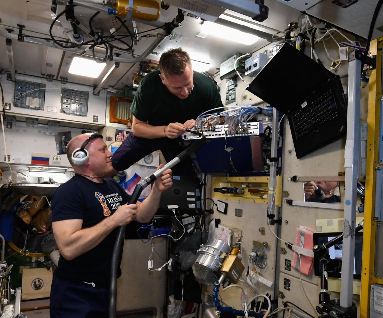 iss056e011715 (June 14, 2018) --- Cosmonauts Oleg Artemyev (at bottom) and Sergey Prokopyev work inside the Zvezda service module performing monthly maintenance on the Smart Switch Router. Credit: Roscosmos
