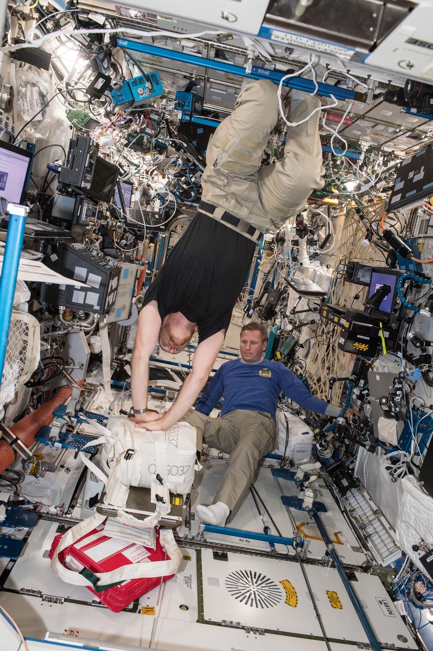 iss056e078440 (July 5, 2018) --- Astronaut Alexander Gerst practices cardiopulmonary resuscitation (CPR) as cosmonaut Sergey Prokopev looks on during an emergency training session aboard the International Space Station. The onboard training provides crewmembers the opportunity to review safety procedures, communication methods and hardware necessary to manage a medical emergency.