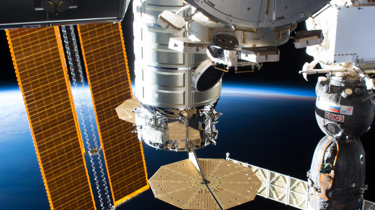 iss056e094392 (July 10, 2018) --- The Northrop Grumman (formerly Orbital ATK) Cygnus resupply ship and its UltraFlex solar arrays figure prominently in this photograph of several International Space Station components with Earth in the background. At left are a set of basketball court-sized solar arrays. In the foreground is the Cupola and a portion of the Tranquility module. At right is the Soyuz MS-09 spacecraft docked to the Rassvet module.