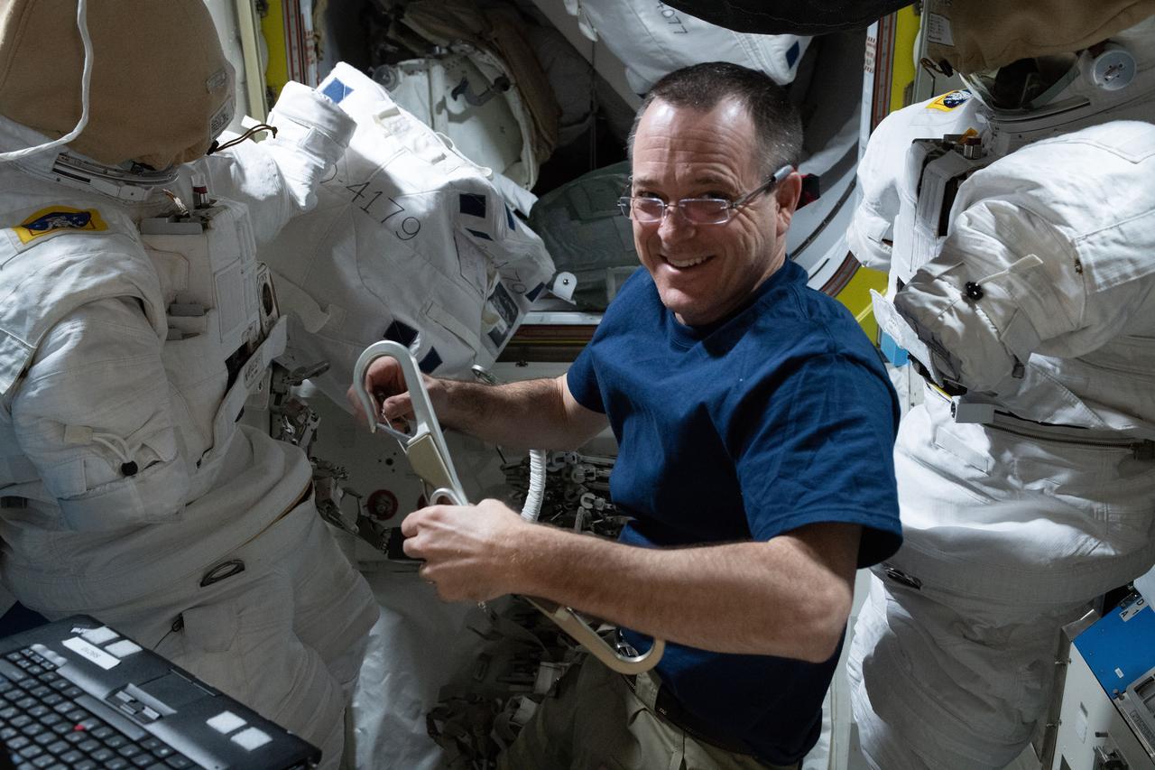 iss056e101070 (Aug. 1, 2018) --- Expedition 56 Flight Engineer Ricky Arnold inspects U.S. spacesuits and tethers in the Quest airlock ahead of a pair of U.S. spacewalks currently planned for September.