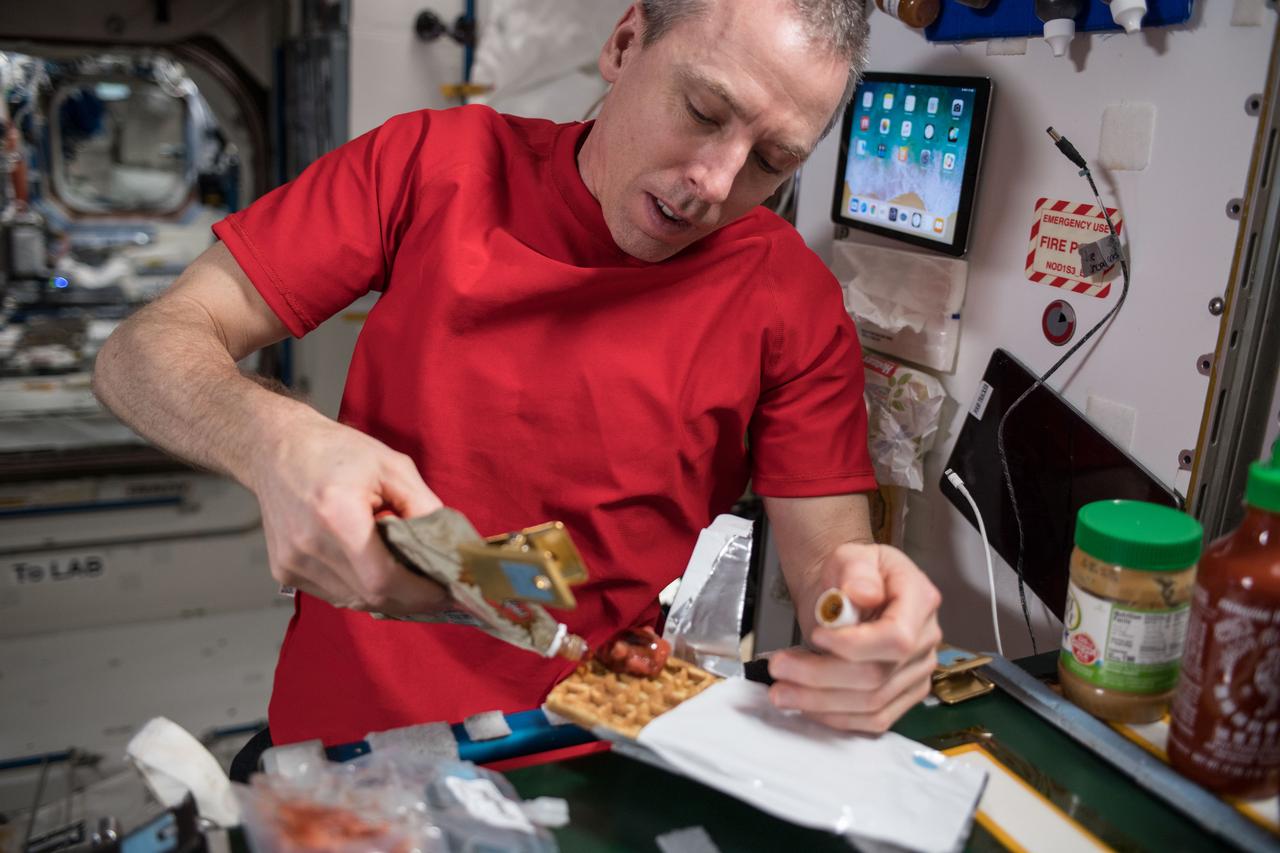 iss056e130422 (July 30, 2018) --- Commander Drew Feustel prepares a meal inside the Unity module which connects the U.S. segment of the International Space Station to the Russian segment.