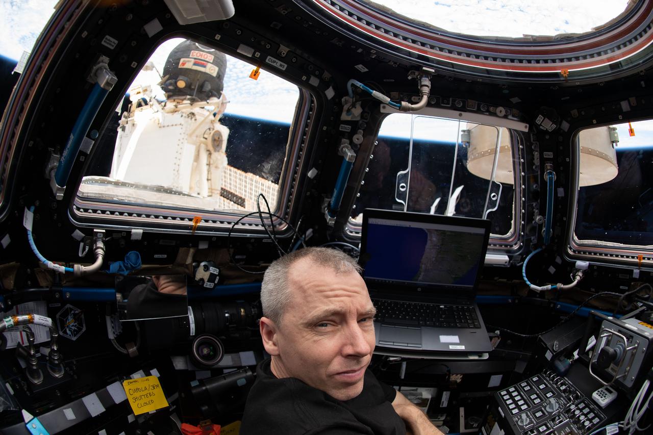 iss056e161464 (Sept. 6, 2018) --- Expedition 56 Commander Drew Feustel of NASA works inside the seven-windowed Cupola as the International Space Station was about to fly over the coast of Chile in South America. Just outside the Cupola and docked to the Rassvet module is the Soyuz MS-09 spacecraft.