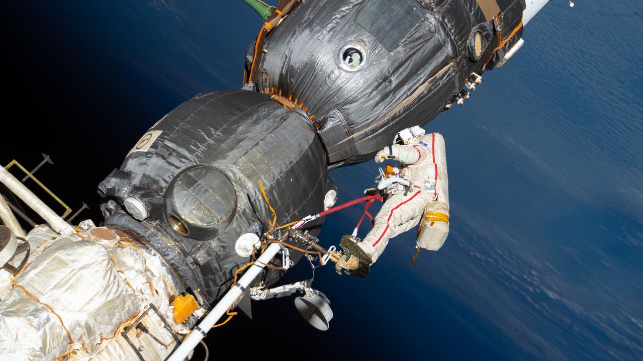 iss057e131661 (Dec. 11, 2018) --- Russian spacewalker Oleg Kononenko (suit with red stripes) works outside the International Space Station over 250 miles above Earth to inspect the Soyuz MS-09 spacecraft. During the spacewalk, he and fellow spacewalker Sergey Prokopyev (out of frame) examined the external hull of the Soyuz crew ship docked to the Rassvet module. The area corresponded with the location of a small hole inside the Soyuz habitation module that was found in August and caused a decrease in the space station’s pressure. The hole was fixed internally with a sealant within hours of its detection. During the spacewalk, Kononenko and Prokopyev collected samples of some of the sealant that extruded through hole to the outer hull before heading back inside the Pirs docking compartment and closing the hatch completing a seven-hour, 45-minute spacewalk.