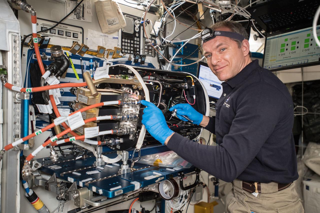 iss058e008801 (Jan. 31, 2019) --- Astronaut David Saint-Jacques of the Canadian Space Agency replaces a control unit and a radiometer inside the Combustion Integrated Rack's (CIR) ACME (Advanced Combustion via Microgravity Experiments) Chamber Insert. The replacement work in the chamber was done on the Unity module's work surface area. The CIR is a fuel and flame research rack housed inside the Destiny laboratory module.
