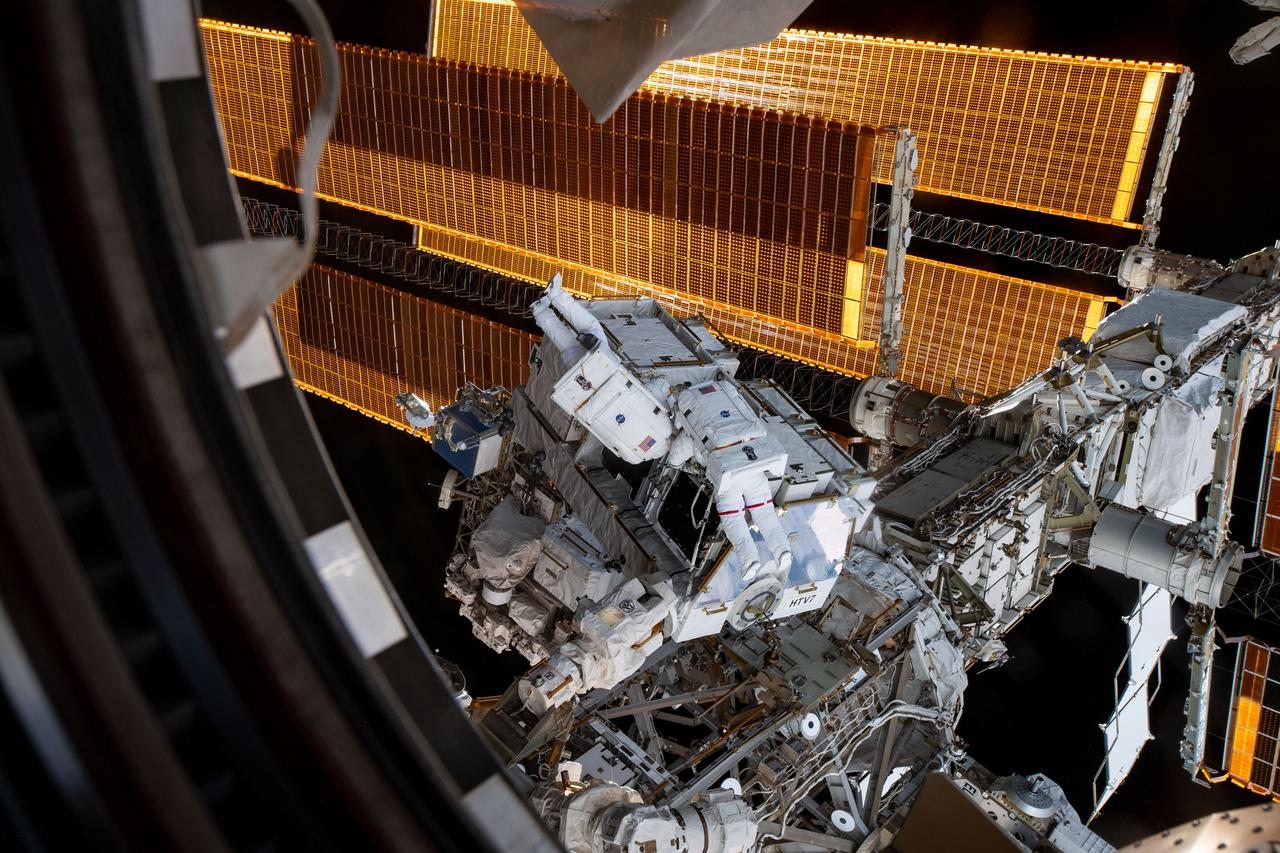 iss059e001506 (March 22, 2019) --- NASA astronauts Nick Hague (suit with no stripes) and Anne McClain (suit with red stripes) work to retrieve batteries and adapter plates from an external pallet during a spacewalk to upgrade the International Space Station's power storage capacity.
