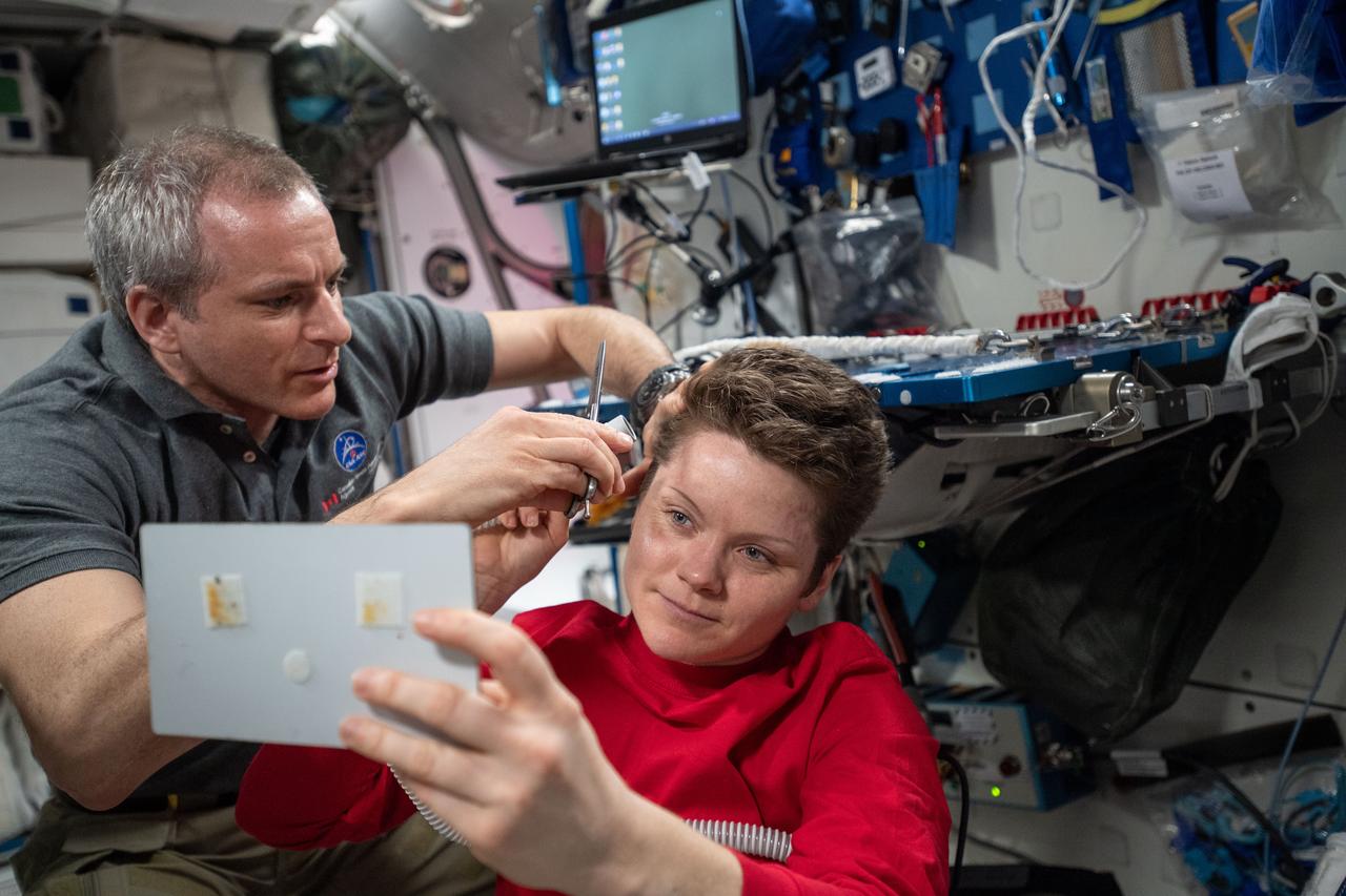 iss059e013076 (April 4, 2019) --- The orbital lab becomes a high-flying hair salon as David Saint-Jacques of the Canadian Space Agency trims NASA astronaut Anne McClain’s hair aboard the International Space Station.