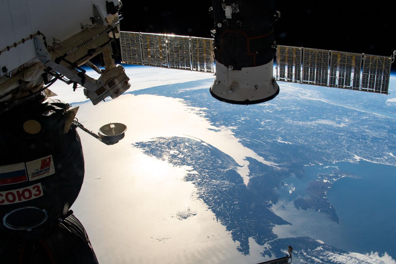 iss059e019071 (April 11, 2019) --- Two Russian spaceships, the Soyuz MS-12 crew ship (left) and the Progress 72 cargo craft, highlight the foreground with the east coast of the United States and Canada in the background. An Expedition 59 crew member took this photograph as the International Space Station orbited 257 miles above the sun glint-lit North Atlantic Ocean.