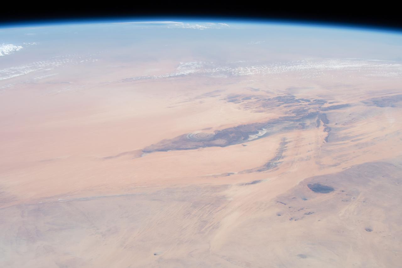 iss059e027887 (April 21, 2019) --- This oblique view from 255 miles above northwest Africa, looking from north to south, shows the "Eye of Sahara" in Mauritania. The circular geologic feature, also known as the Richat Structure, is thought to be caused by an uplifted dome—geologists would classify it as a domed anticline—that has been eroded to expose the originally flat rock layers.