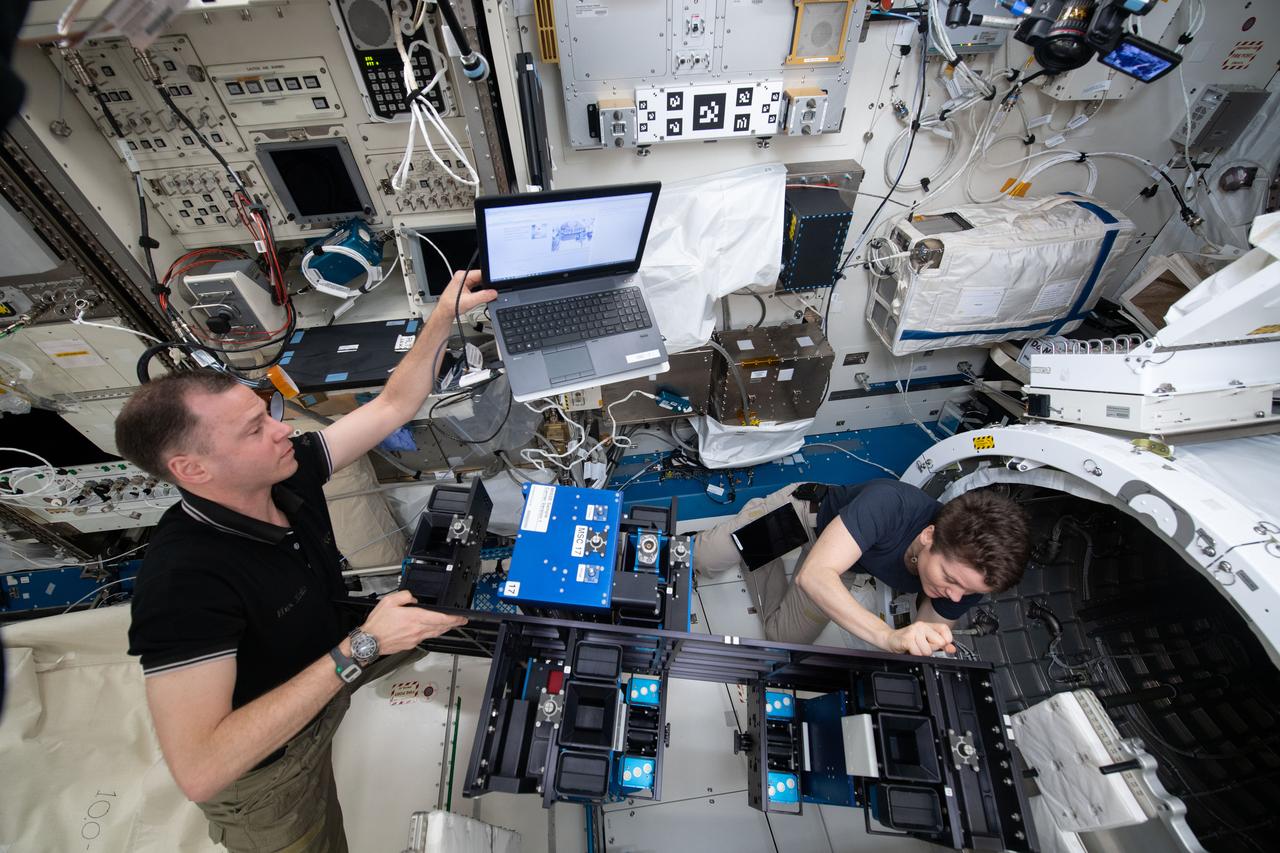 iss059e034507 (April 23, 2019) --- NASA astronauts Nick Hague and Anne McClain install the Materials ISS Experiment-Flight Facility (MISSE-FF) gear inside the Japanese Kibo laboratory module’s airlock before depressurizing the unit. MISSE-FF contains new materials exposure experiments ready for deployment outside Kibo. The study will help scientists understand how radiation, the vacuum of space and micrometeoroids affect a variety of materials.