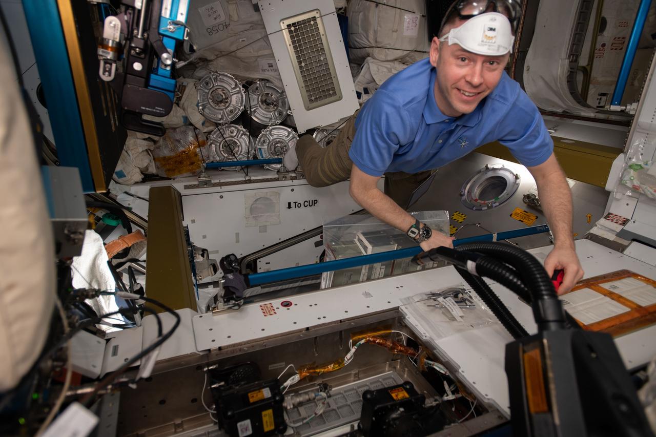 iss059e036143 (April 29, 2019) --- Expedition 59 Flight Engineer and NASA astronaut Nick Hague wears personal protection gear while working to remove bacteria filters and replacing them with charcoal filters inside the International Space Station's Tranquility module.