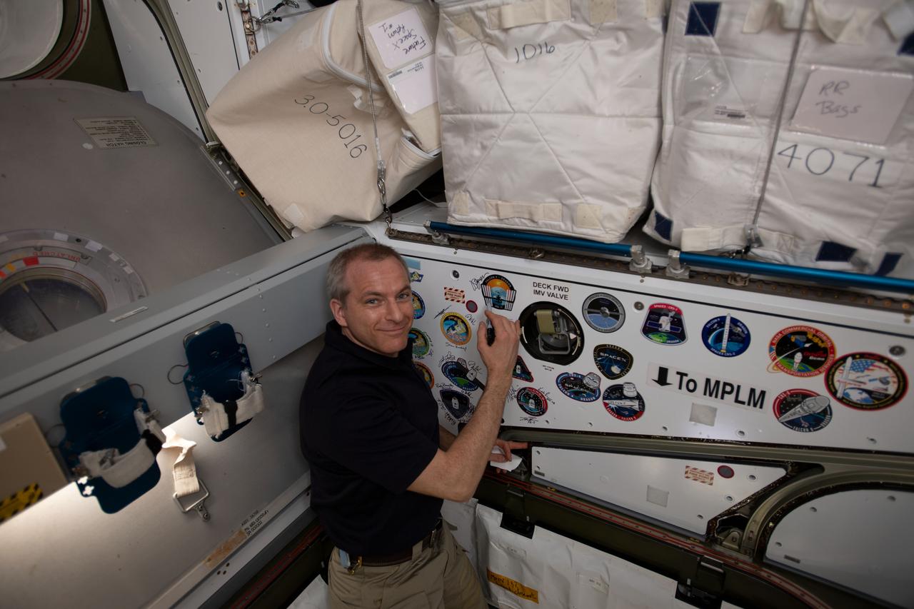 iss059e087858 (June 3, 2019) --- Canadian Space Agency astronaut David Saint-Jacques signs the inside of the vestibule between the SpaceX Dragon cargo craft and the Harmony module. The hatch to Dragon was later closed and the resupply ship detached from Harmony before it was released from the grips of the Canadarm2 robotic arm. Dragon spent nearly a month attached to the International Space Station.