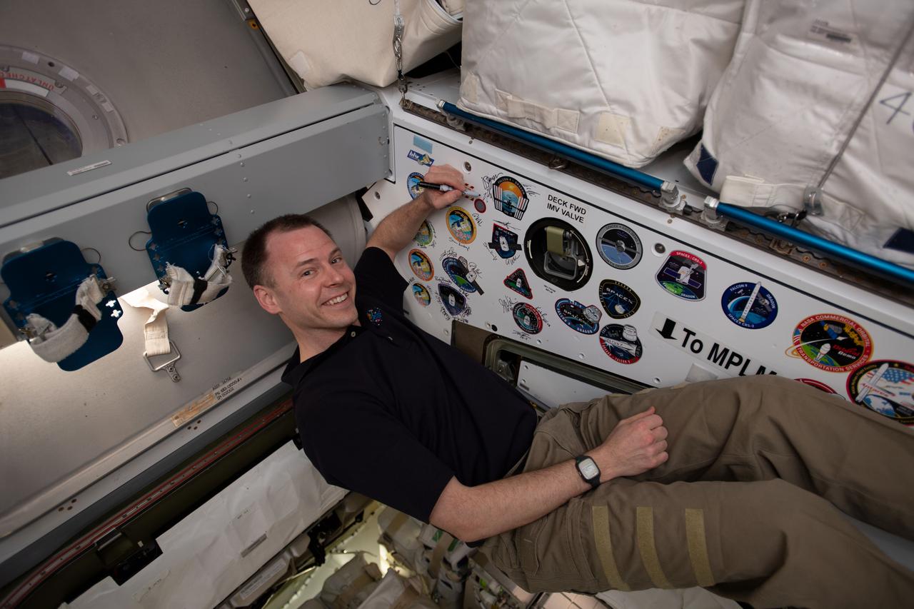 iss059e087866 (June 3, 2019) --- NASA astronaut Nick Hague signs the inside of the vestibule between the SpaceX Dragon cargo craft and the Harmony module. The hatch to Dragon was later closed and the resupply ship detached from Harmony before it was released from the grips of the Canadarm2 robotic arm. Dragon spent nearly a month attached to the International Space Station.