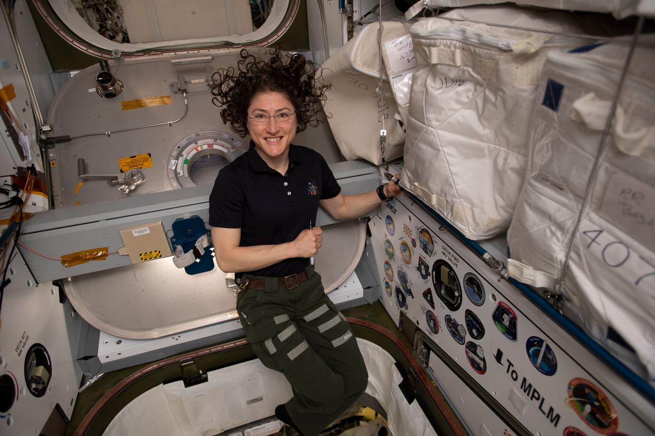 iss059e087869 (June 3, 2019) --- NASA astronaut Christina Koch poses for a portrait inside of the vestibule between the SpaceX Dragon cargo craft and the Harmony module. The hatch to Dragon was later closed and the resupply ship detached from Harmony before it was released from the grips of the Canadarm2 robotic arm. Dragon spent nearly a month attached to the International Space Station.