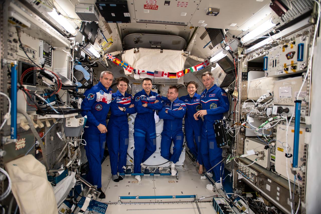 iss059e098799 (June 8, 2019) --- The six-member Expedition 59 crew gathers for a portrait inside the Kibo laboratory module from the Japan Aerospace Exploration Agency. From left are, astronauts David Saint-Jacques and Anne McClain; Cosmonauts Oleg Kononenko and Alexey Ovchinin; and astronauts Christina Koch and Nick Hague.