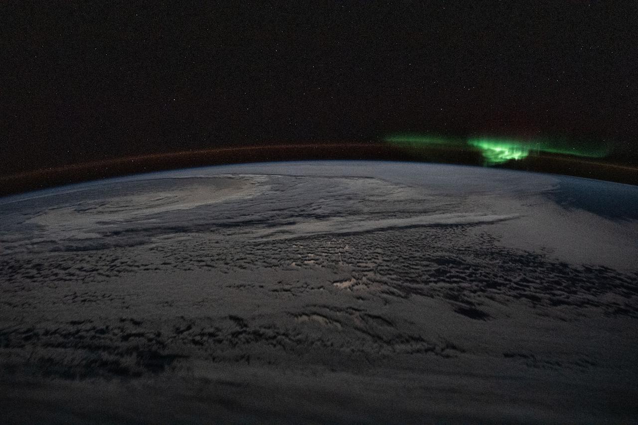 iss059e119533 (June 21, 2019) --- The atmospheric glow and a wispy aurora australis, also known as the "southern lights," frame a cloud-covered Earth as the International Space Station orbited 254 miles above the Indian Ocean due east of the territory of French Southern and Antarctic Lands.