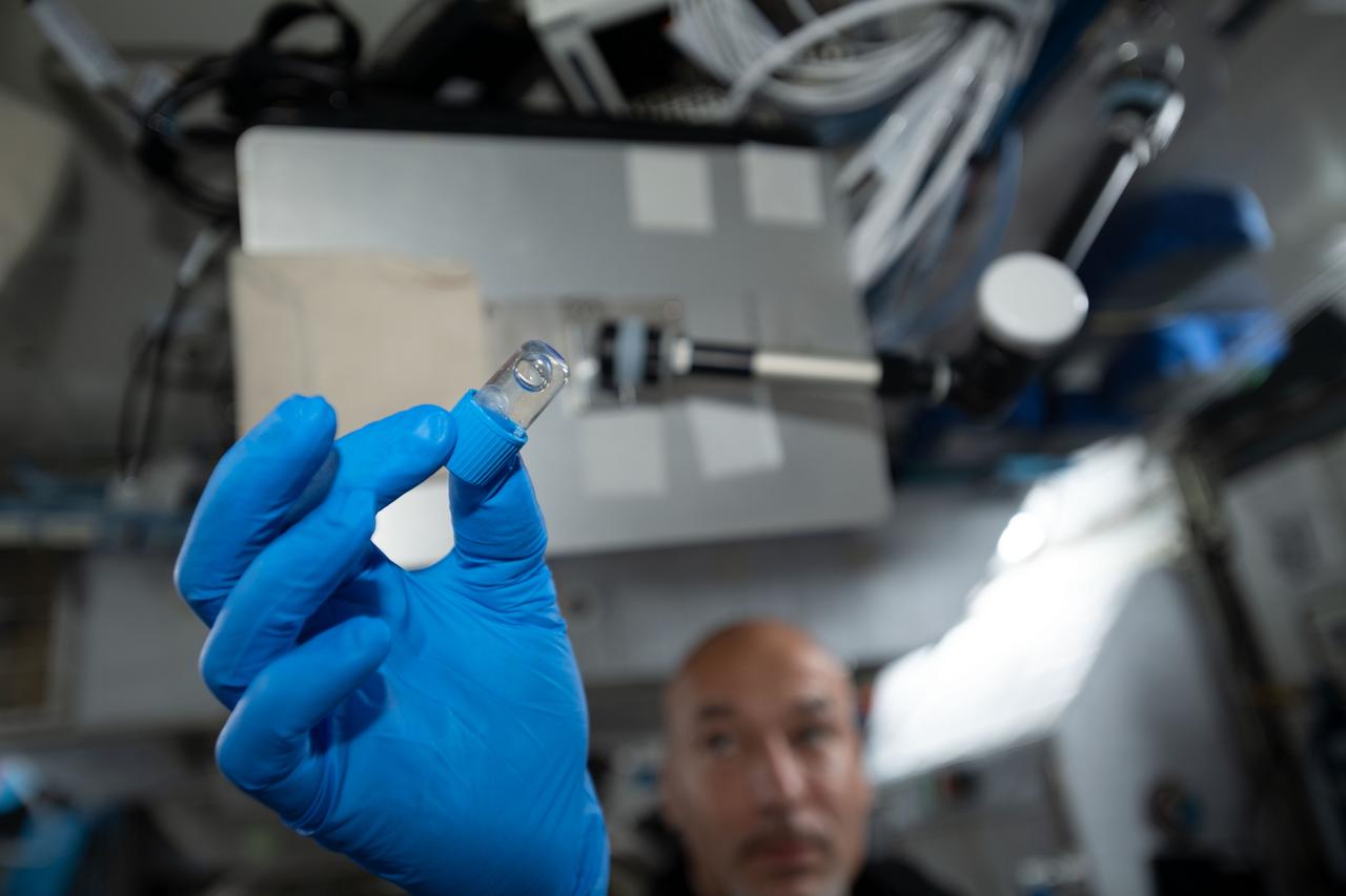 iss060e023994 (8/7/2019) --- European Space Agency (ESA) astronaut Luca Parmitano is shown holding a Amyloid Aggregation Blue Jar. The cap colors are used to distinguish the incubation times. The aim of the Amyloid Aggregation investigation is to assess if amyloid fibrils aggregation is affected by microgravity in order to identify a possible professional risk in astronauts spending long periods on board the ISS. The knowledge gained could contribute to the designing of innovative therapeutic strategies for the treatment of Alzheimer’s Disease and for other diseases characterized by protein accumulation.
