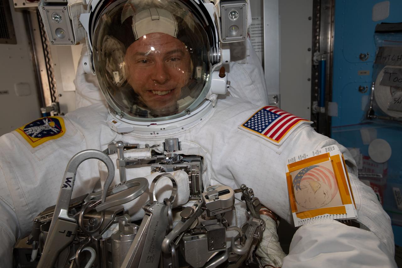 iss060e038228 (Aug. 21, 2019) --- NASA astronaut Nick Hague is pictured in his U.S. spacesuit inside the International Space Station's Quest airlock preparing to begin a six-hour and 32-minute spacewalk to install the orbiting lab’s second commercial crew vehicle docking port, the International Docking Adapter-3 (IDA-3). The IDA-3 will accommodate the future arrivals of Boeing CST-100 Starliner and SpaceX Crew Dragon commercial crew spacecraft.