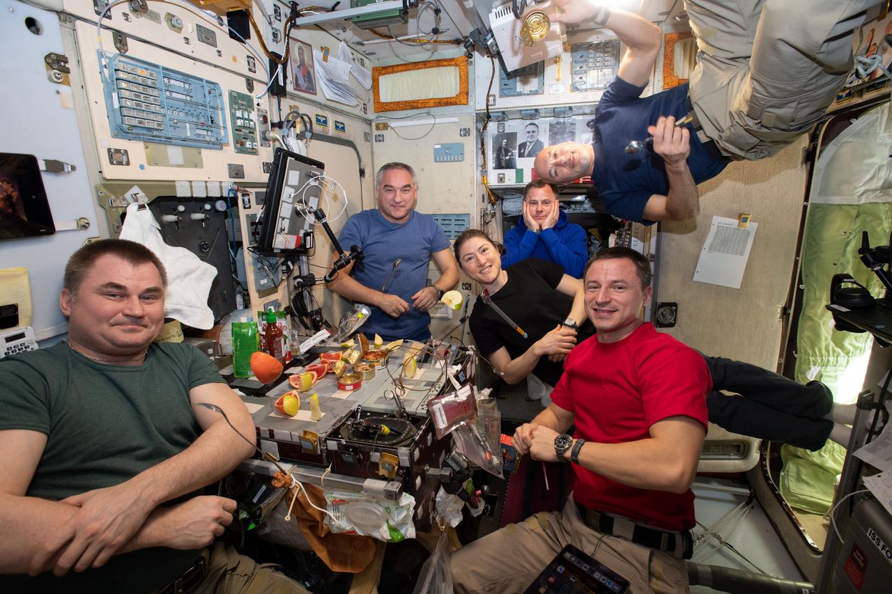 iss060e060255 (Sept. 11, 2019) --- The six-member Expedition 60 crew is gathered together for dinner inside the galley of the Zvezda service module. The space residents dine on a variety of fresh fruit and canned and pre-packaged dishes. Condiments commonly available in kitchen pantries on Earth are also on the station to spice up a crew's space meals.