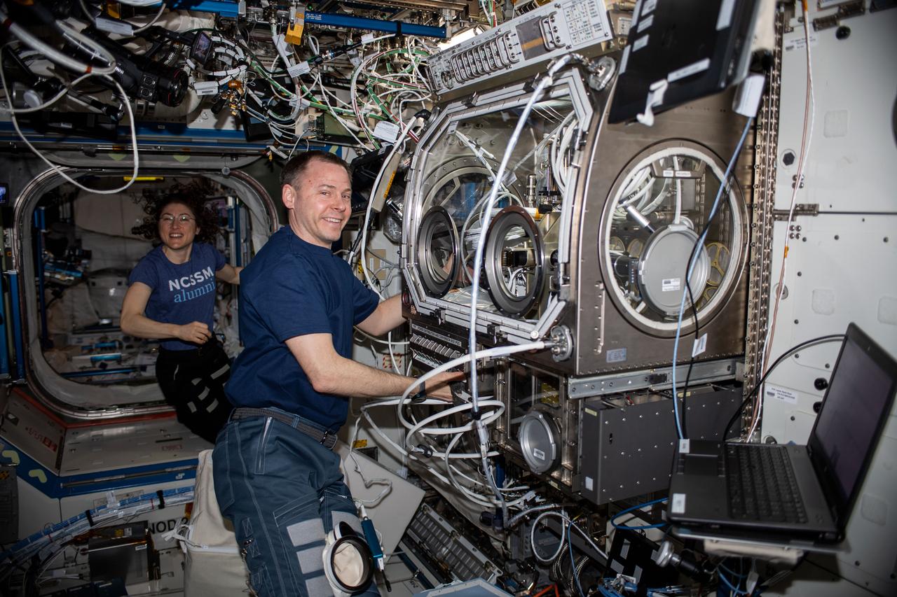 iss060e073417 (Sept. 19, 2019) --- NASA astronauts Christina Koch and Nick Hague are pictured inside the U.S. Destiny laboratory module. Hague was setting up the Microgravity Sciences Glovebox to begin operations for the Ring-Sheared Drop experiment to understand how fluids flow in the human body and other materials. Koch had finished an exercise session after jogging on the COLBERT (Combined Operational Load Bearing External Resistance Treadmill).