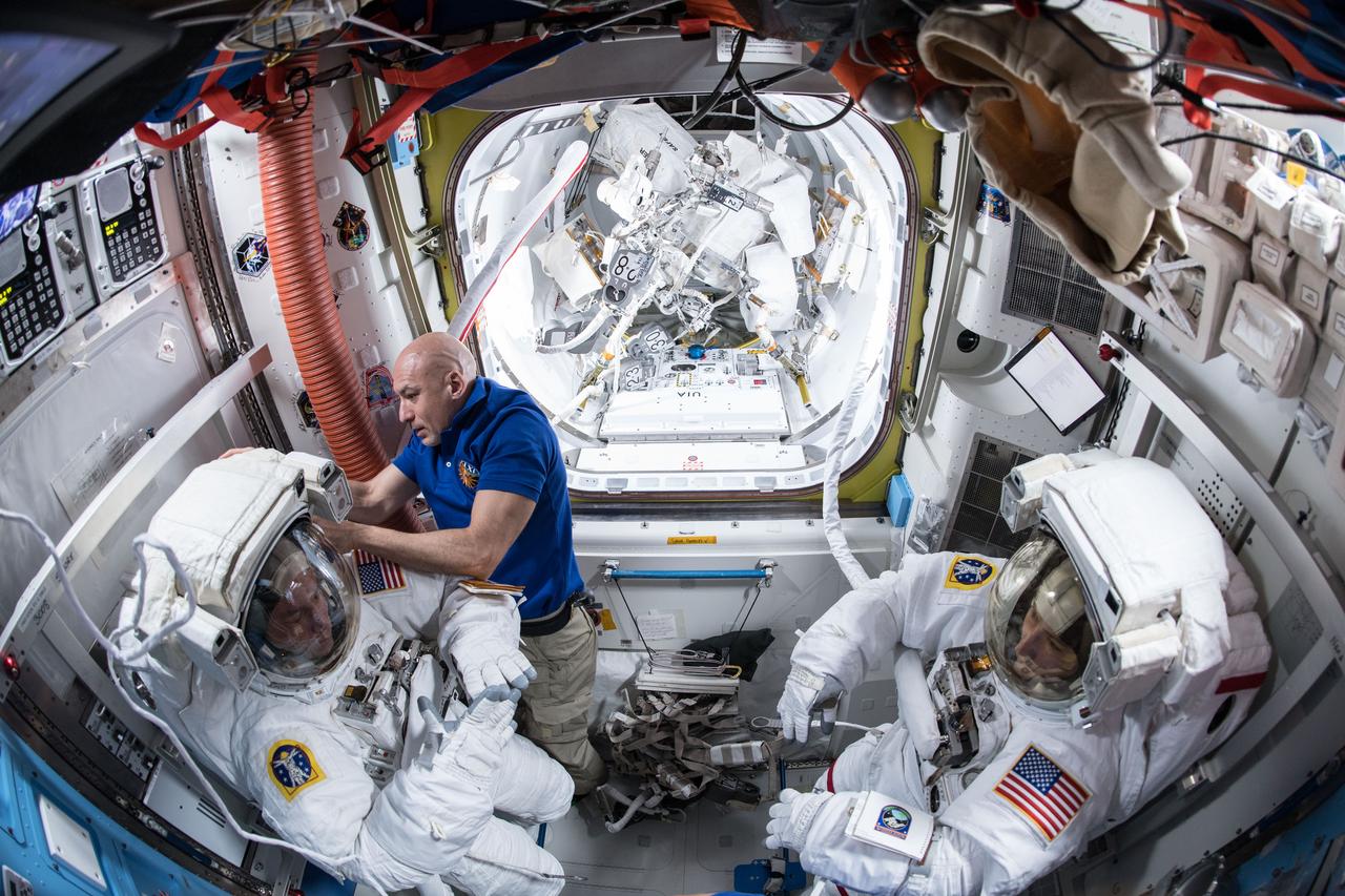 iss061e003210 (Oct. 6, 2019) --- Expedition 61 Commander Luca Parmitano of ESA (European Space Agency) assists NASA astronauts Andrew Morgan (left) and Christina Koch (right) in their U.S. spacesuits. The NASA spacewalkers would go on to conduct a seven hour and one minute spacewalk to begin the latest round of upgrading the station's large nickel-hydrogen batteries with newer, more powerful lithium-ion batteries.
