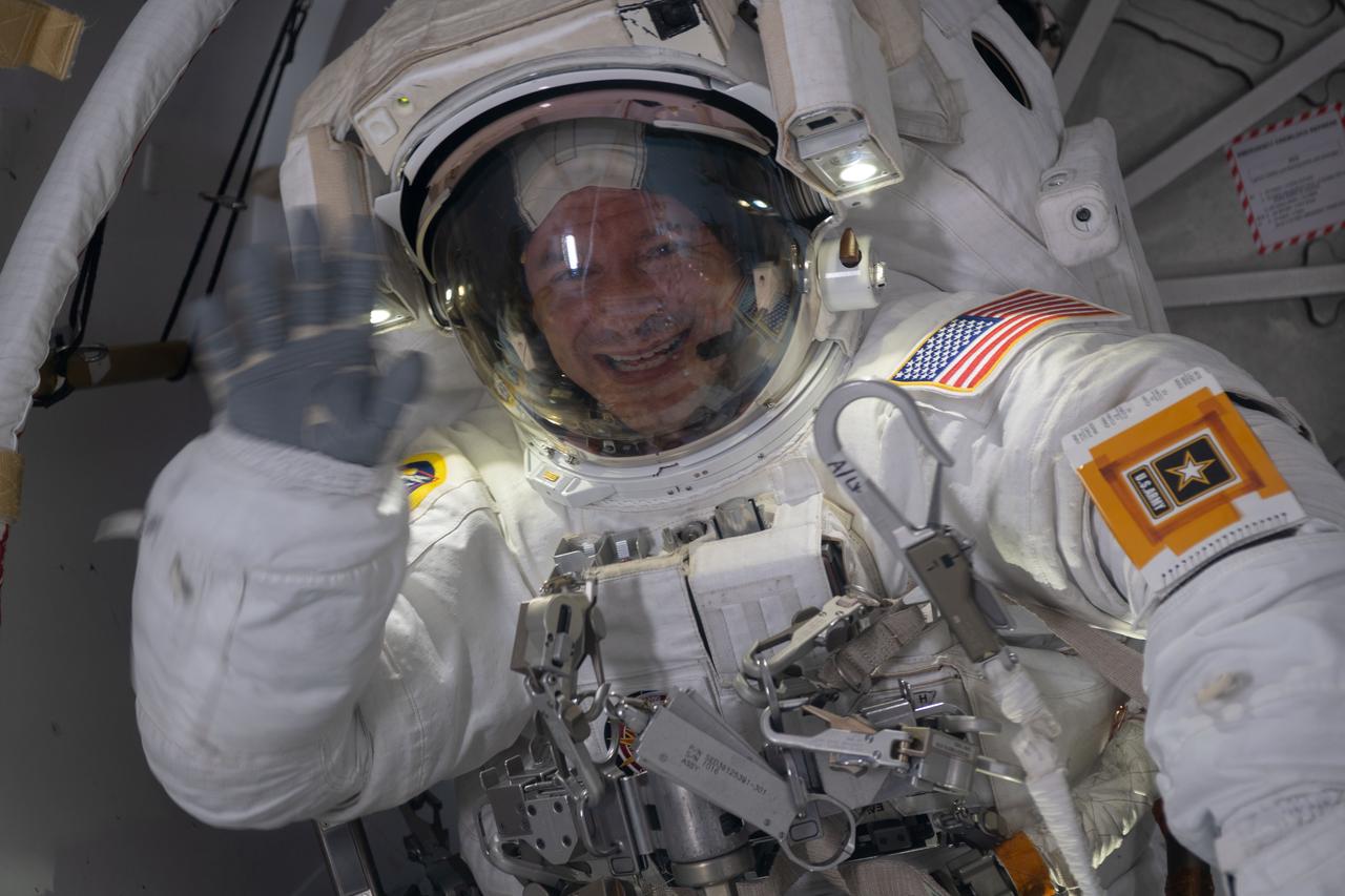 iss061e003683 (Oct. 6, 2019) --- NASA astronaut Andrew Morgan waves from inside the crew lock portion of the Quest airlock where spacewalks in U.S. spacesuits are staged. He would go on to conduct a seven hour and one minute spacewalk with NASA astronaut Christina Koch to begin the latest round of upgrading the station's large nickel-hydrogen batteries with newer, more powerful lithium-ion batteries.