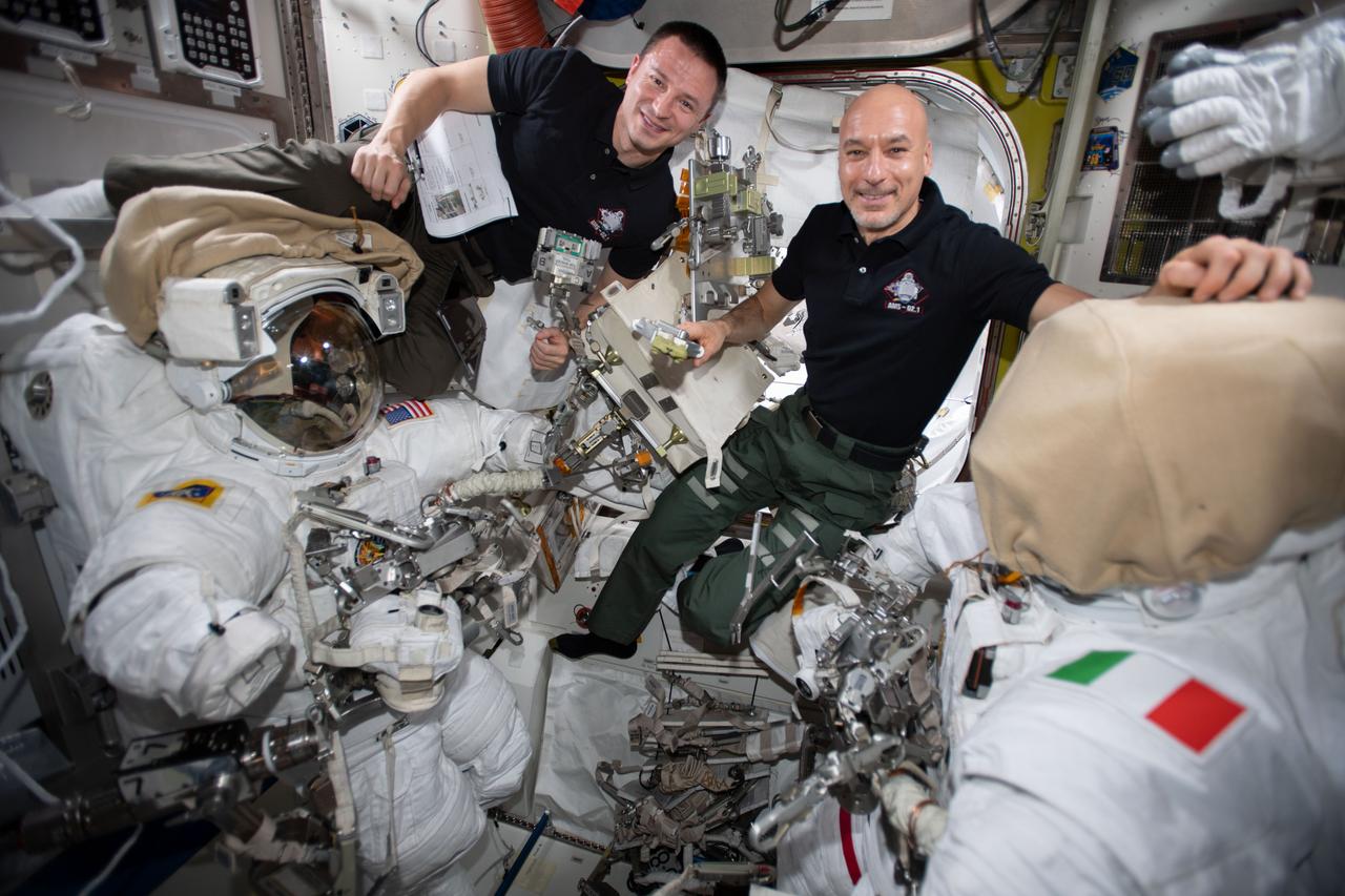 iss061e033873 (Nov. 11, 2019) --- (From left) NASA astronaut Andrew Morgan and ESA (European Space Agency) Commander Luca Parmitano work inside the Quest airlock checking U.S. spacesuits and spacewalking tools. The duo will conduct several spacewalks in November to upgrade the Alpha Magnetic Spectrometer's (AMS) thermal control system. The AMS is the International Space Station's cosmic particle detector.