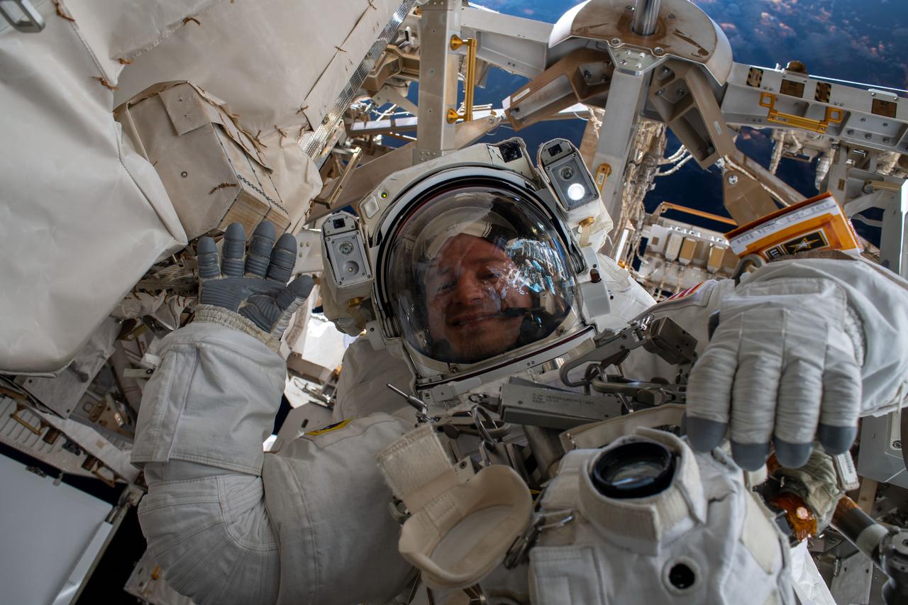iss061e040708 (Nov. 15, 2019) --- NASA astronaut Andrew Morgan waves as he is photographed during the first spacewalk to repair the Alpha Magnetic Spectrometer, a cosmic particle detector on the International Space Station.
