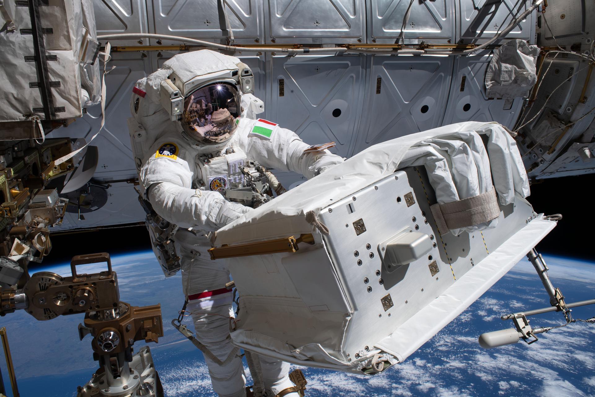 ESA (European Space Agency) astronaut Luca Parmitano, attached to the Canadarm2 robotic arm, carries the new thermal pump system that was installed on the Alpha Magnetic Spectrometer (AMS) during the third spacewalk to upgrade the AMS, the International Space Station's cosmic particle detector.