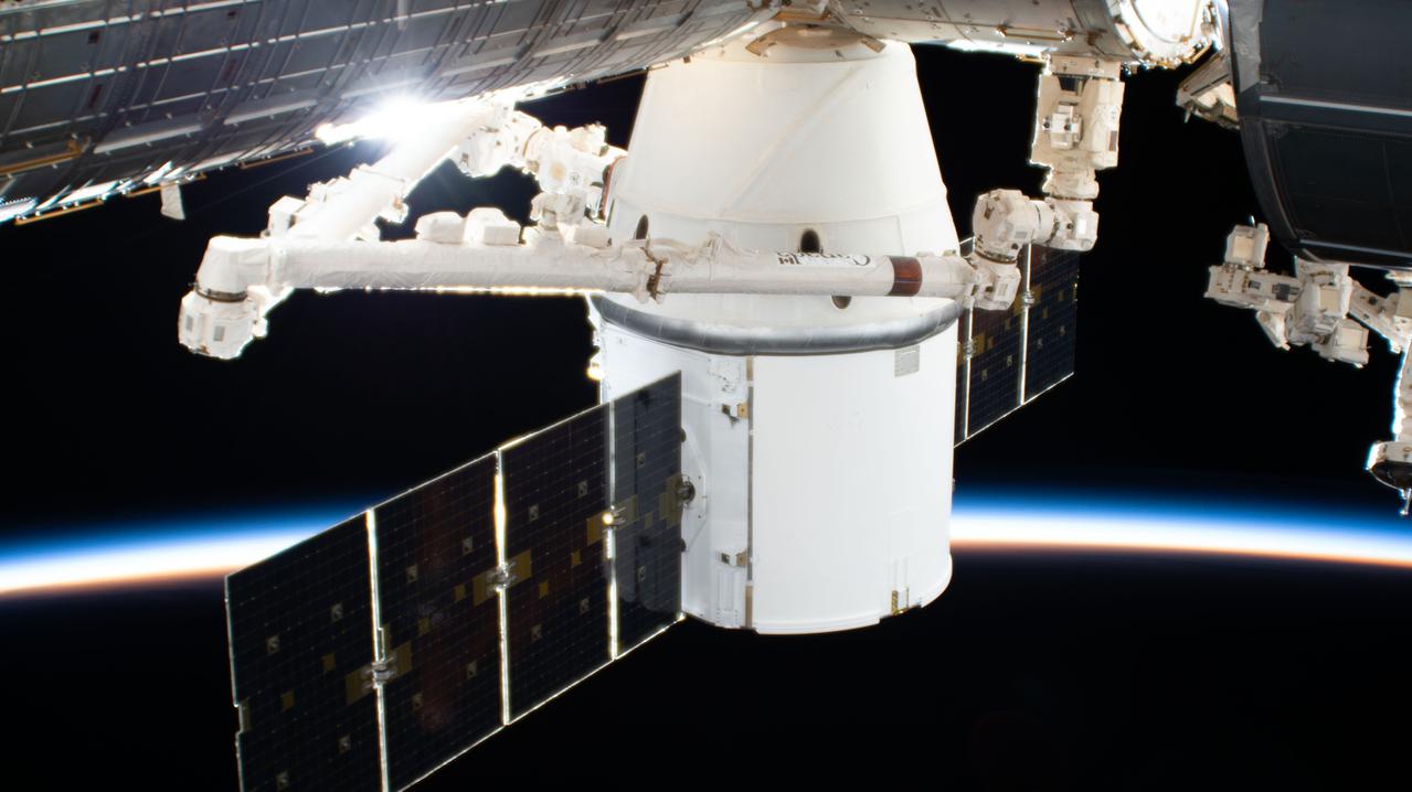 iss061e067980 (Dec. 8, 2019) --- The SpaceX Dragon resupply ship is pictured in the grip of the Canadarm2 robotic arm after it was installed to the Harmony module. The International Space Station was orbiting 270 miles above the South Atlantic Ocean during an orbital sunset when this photograph was taken by an external high definition camera.