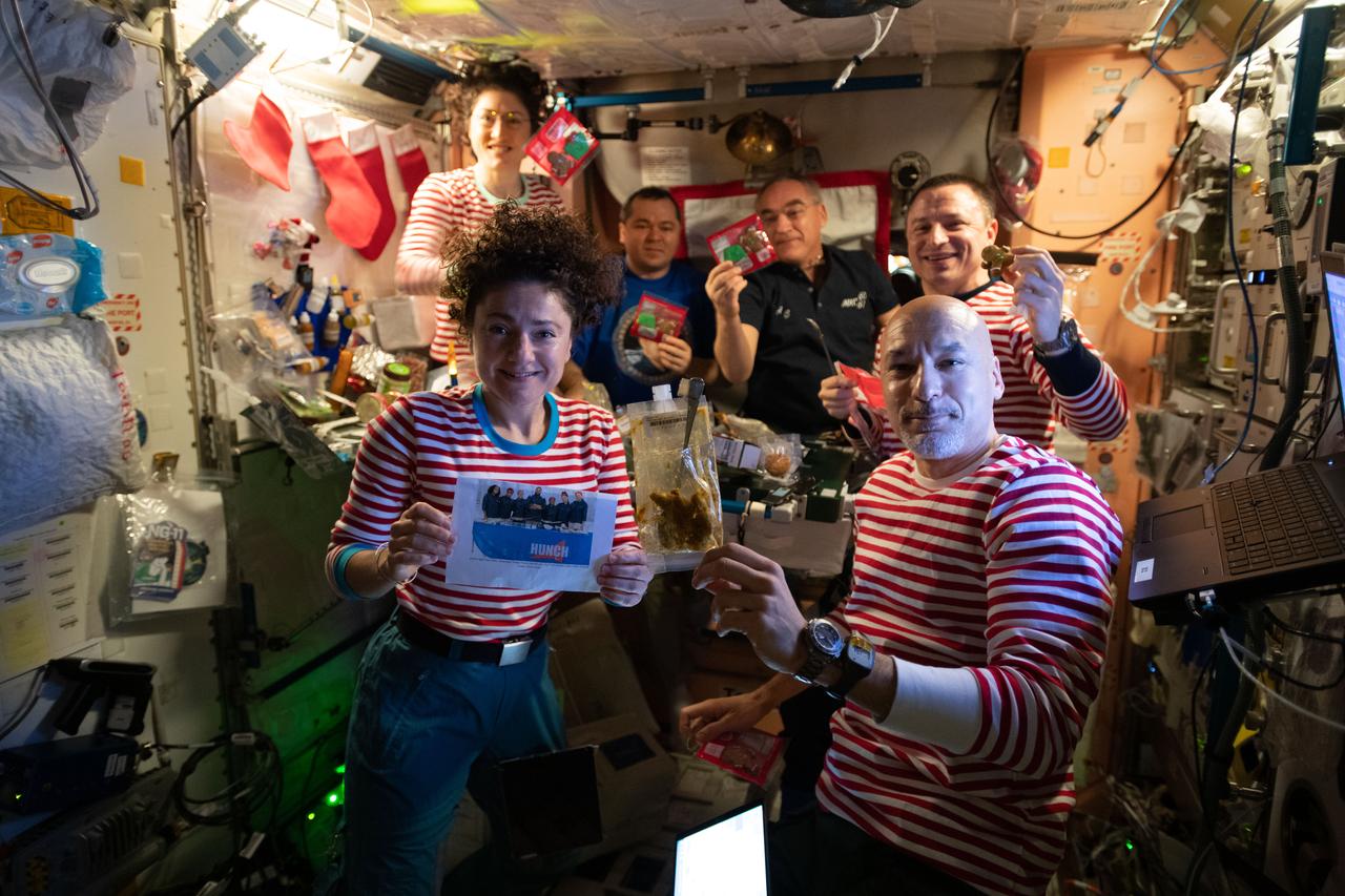 iss061e096558 (Dec. 25, 2019) --- The Expedition 61 crew celebrates Christmas day with a brunch inside the International Space Station's Unity module decorated with stockings, flashlight "candles" and a Christmas tree banner. Clockwise from bottom left are, NASA Flight Engineers Jessica Meir and Christina Koch, Roscosmos Flight Engineers Oleg Skripochka and Alexander Skvortsov, NASA Flight Engineer Drew Morgan, and Commander Luca Parmitano of the European Space Agency (ESA).