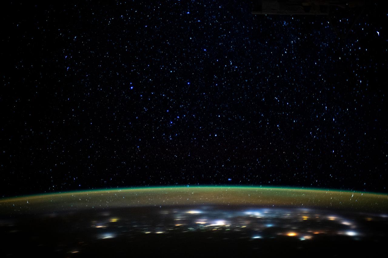 iss061e110462 (Dec. 29, 2019) --- Stars glitter in the night sky above an atmospheric glow that blankets the city lights as the International Space Station orbited 260 miles above northern Iran as it was about to cross the Caspian Sea.