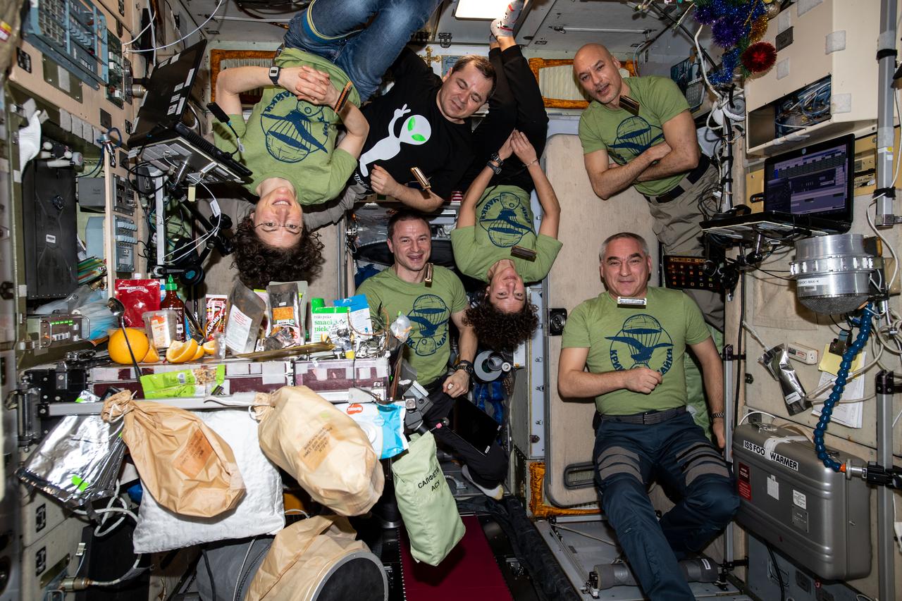 iss061e112462 (Dec. 31, 2019) --- The six-member Expedition 61 crew is gathered together inside the Zvezda service module for a New Year's Eve meal. Clockwise from top left are, Flight Engineers Christina Koch of NASA and Oleg Skripochka of Roscosmos; Commander Luca Parmitano of ESA (European Space Agency); Flight Engineers Alexander Skvortsov of Roscosmos and Jessica Meir and Andrew Morgan, both from NASA.