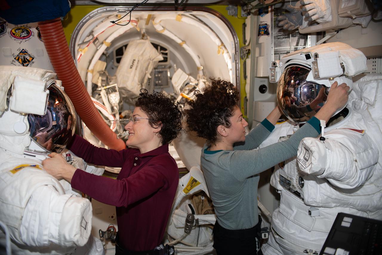 iss061e121950 (Jan. 15, 2020) --- NASA astronauts Christina Koch (left) and Jessica Meir work on their U.S. spacesuits ahead of a spacewalk they conducted to install new lithium-ion batteries that store and distribute power collected from solar arrays on the station’s Port-6 truss structure.