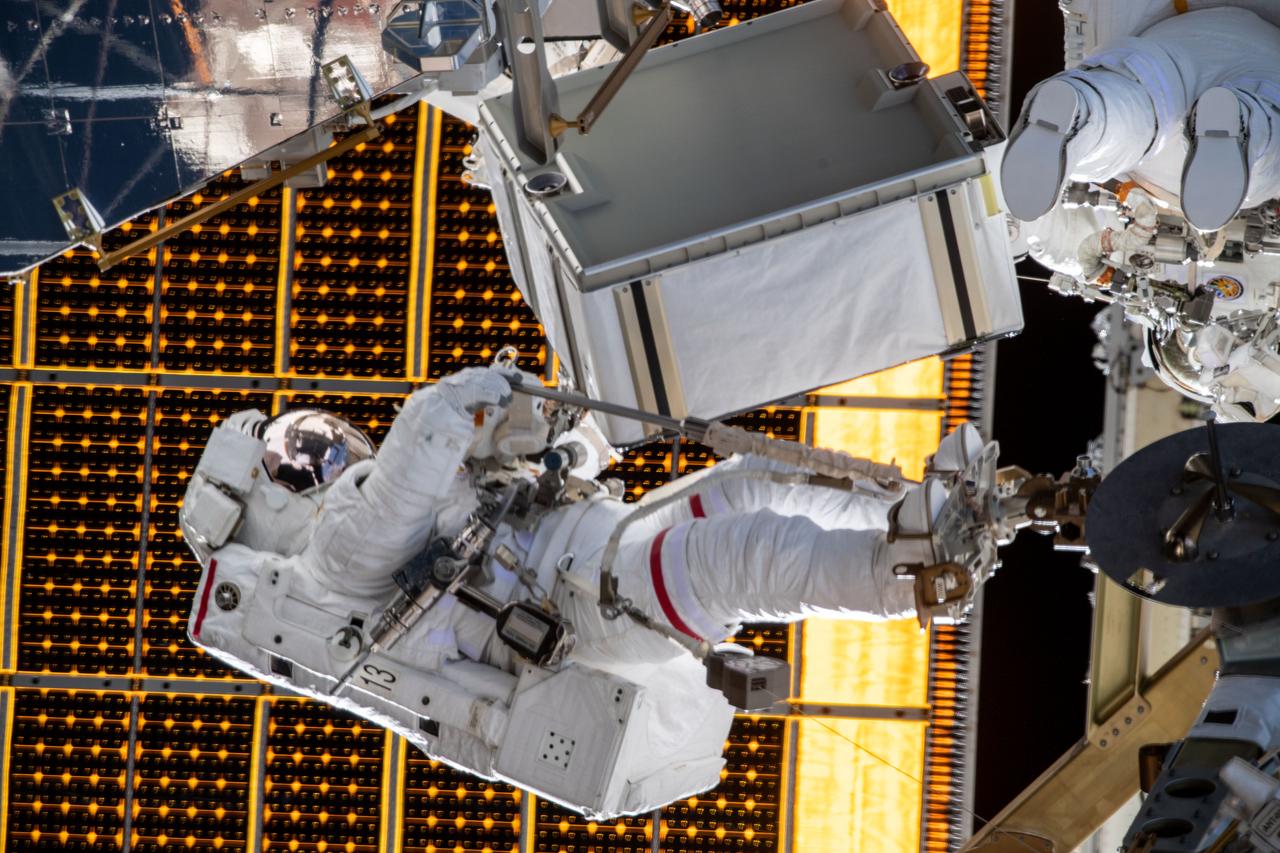 iss061e129592 (Jan. 20, 2020) --- NASA astronaut Jessica Meir is attached to an articulating portable foot restraint during a spacewalk with NASA astronaut Christina Koch (upper right) to finalize upgrading power systems on the International Space Station's Port-6 truss structure.