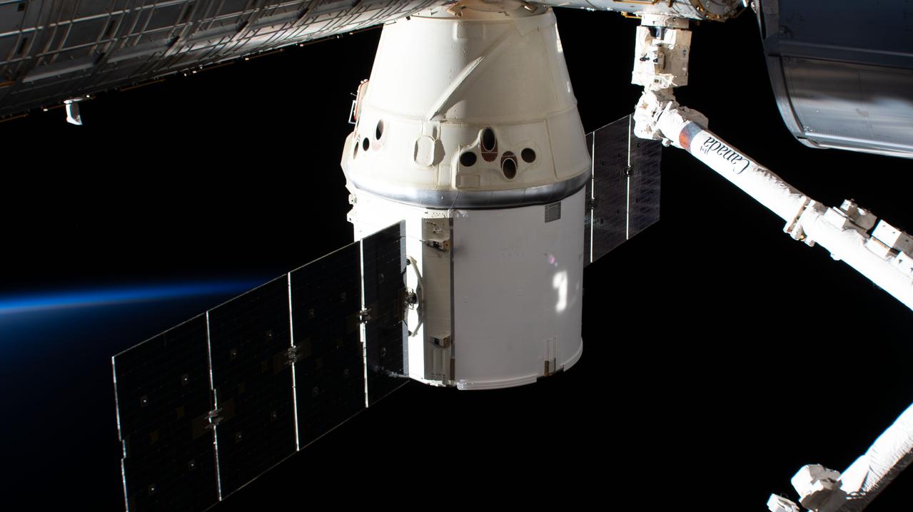 iss062e115307 (March 24, 2020) --- The SpaceX Dragon resupply ship is pictured attached to the International Space Station's Harmony module with the Canadarm2 robotic arm at right.