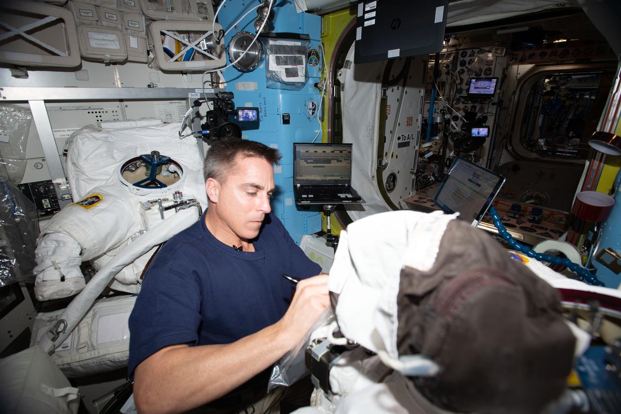 iss063e003861 (April 29, 2020) --- NASA astronaut and Expedition 63 Commander Chris Cassidy cleans cooling loops, replaces components and conducts leak checks inside U.S. spacesuits aboard the International Space Station's Quest airlock.