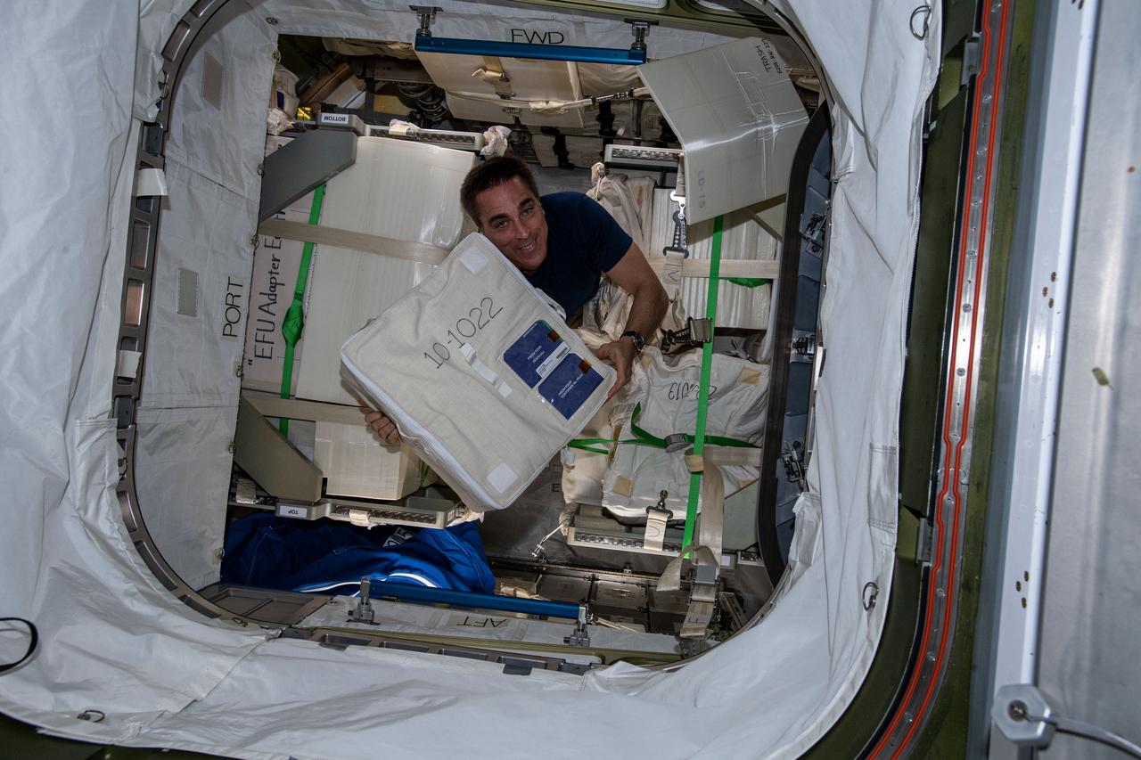 iss063e017199 (May 26, 2020) --- NASA astronaut and Expedition 63 Commander Chris Cassidy unloads a bag packed with fresh food from Japan's resupply ship, the H-II Transfer Vehicle-9 (HTV-9), that had arrived at the International Space Station the day before.